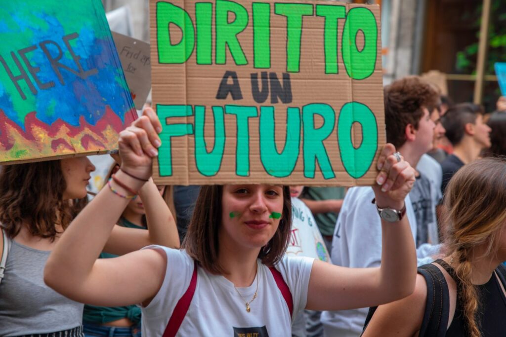 Young adults in Milan rally for climate action, holding signs in a dynamic protest.